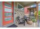 Relaxing front porch with seating, featuring a brick accent wall and a stylish orange entry door at 21451 E 60Th Ave, Aurora, CO 80019