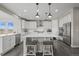 Well-lit kitchen boasts white cabinets, stainless steel appliances, and island with bar stool seating at 9021 Swan River St, Littleton, CO 80125