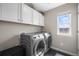 Well-lit laundry room featuring gray machines, stylish cabinets, and a bright window at 9021 Swan River St, Littleton, CO 80125