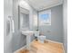Stylish bathroom with wood floors, textured gray walls, a pedestal sink, and natural light at 853 Huntington Dr, Highlands Ranch, CO 80126