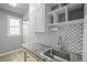 Clean laundry room with modern patterned backsplash, a utility sink and ample storage space, and a bright window at 853 Huntington Dr, Highlands Ranch, CO 80126