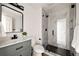Modern bathroom with marble tiled shower, gray vanity, black fixtures, and wood-look flooring at 9316 W Utah Ave, Lakewood, CO 80232