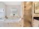 Bright bathroom featuring a soaking tub, separate glass-enclosed shower, and window providing natural light at 2692 N Raleigh St, Denver, CO 80212