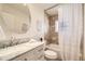 Bathroom featuring a double vanity with marble countertop, a round mirror, and a tiled shower with glass door at 2692 N Raleigh St, Denver, CO 80212