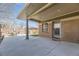 A spacious covered patio with brick siding, featuring an outdoor dining area and access to a grassy backyard at 2692 N Raleigh St, Denver, CO 80212