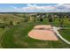 An aerial view of a baseball field with well-groomed infield, lush green outfield, and scenic neighborhood backdrop at 9856 Keenan St, Highlands Ranch, CO 80130