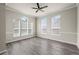 Bright living room featuring large windows, modern ceiling fan, and sleek, dark-toned hardwood floors at 9856 Keenan St, Highlands Ranch, CO 80130