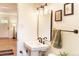 Tastefully designed bathroom featuring pedestal sink, updated fixtures, artwork and hardwood floors flowing to the next room at 2294 W Parkhill Ave, Littleton, CO 80120