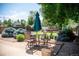 Outdoor patio dining area with seating for four under an umbrella, surrounded by mature trees and landscaping at 2294 W Parkhill Ave, Littleton, CO 80120