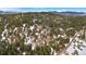 An aerial view shows scattered houses nestled among dense trees and snowy patches on a hilly landscape at 25019 N Mountain Park Dr, Evergreen, CO 80439
