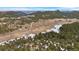 Aerial view of rural property with evergreen trees, a pond, and other homes in the distance at 25019 N Mountain Park Dr, Evergreen, CO 80439