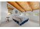 Bedroom with a vaulted wood ceiling, three large windows, and a comfortable queen-size bed with a striped comforter at 25019 N Mountain Park Dr, Evergreen, CO 80439