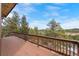 Expansive wooden deck featuring wood railings and peaceful views of evergreen trees against a beautiful blue sky at 25019 N Mountain Park Dr, Evergreen, CO 80439
