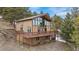 Exterior view of home with wooden deck, surrounded by trees and nature, showcasing its tranquil setting at 25019 N Mountain Park Dr, Evergreen, CO 80439