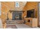 Living room showcasing a cozy fireplace, adjacent to a television and wood-paneled walls at 25019 N Mountain Park Dr, Evergreen, CO 80439
