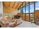 Bright living room with a vaulted ceiling, wood paneling, a fireplace, and floor-to-ceiling windows at 25019 N Mountain Park Dr, Evergreen, CO 80439