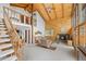 Open-concept living room with a vaulted ceiling, wood paneling, a fireplace, and a staircase to the second floor at 25019 N Mountain Park Dr, Evergreen, CO 80439