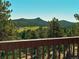 Breathtaking view of rolling hills, lush trees, and serene skies from a wooden deck at 25019 N Mountain Park Dr, Evergreen, CO 80439