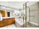 Bright bathroom with a soaking tub, glass enclosed shower, double vanity, and a large window providing natural light at 17705 W 63Rd Dr, Golden, CO 80403