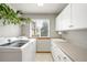 Laundry room with a washing machine, dryer, sink, storage cabinets, counter space, and natural light from a window at 17705 W 63Rd Dr, Golden, CO 80403