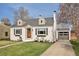 Inviting home featuring a manicured lawn, brick accents, dormer windows, and an attached garage for convenient parking at 2830 Forest St, Denver, CO 80207