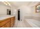 Primary bathroom with double sinks, oak cabinets, large tub and tiled floor with stained glass window at 2072 Skylark Ct, Longmont, CO 80503