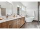 Modern bathroom features double sinks, wood vanity, and a freestanding tub with sleek fixtures at 960 Quitman St, Denver, CO 80204
