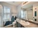 Bright bathroom with gray vanity, tile floors, and mountain-themed accent wall and sheer white curtains at 5624 Killdeer St, Brighton, CO 80601
