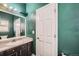 A full bathroom with a sink, mirror, and textured green walls at 5624 Killdeer St, Brighton, CO 80601