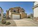 Tan two-story home featuring a large driveway, two car garage, and rock landscaping at 5624 Killdeer St, Brighton, CO 80601