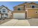 Tan two-story home featuring a large driveway, two car garage, and rock landscaping at 5624 Killdeer St, Brighton, CO 80601