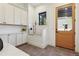 Bright laundry room features a dog shower, white cabinets, and wood door to outside at 2511 S Columbine St, Denver, CO 80210