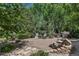 Relaxing backyard featuring a fire pit and multiple seating areas surrounded by lush trees and plants at 6633 E 166Th Pl, Brighton, CO 80602