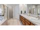 Bright bathroom with dual sinks, wood cabinets, and a glass-enclosed shower at 6633 E 166Th Pl, Brighton, CO 80602