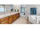 Spacious bathroom featuring a soaking tub, dual sinks, and classic wood cabinetry at 6633 E 166Th Pl, Brighton, CO 80602