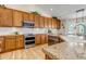 Charming kitchen featuring wood cabinets, granite countertops, and modern stainless steel appliances at 6633 E 166Th Pl, Brighton, CO 80602
