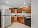 Basement kitchenette with wood cabinets, a stainless-steel refrigerator, and black appliances at 6633 E 166Th Pl, Brighton, CO 80602