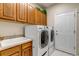 Functional laundry room with sink, wooden cabinets, and modern washer and dryer at 6633 E 166Th Pl, Brighton, CO 80602