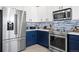 Modern kitchen featuring stainless steel appliances, stylish blue and white cabinets, and stone backsplash at 11671 Elkhart, Brighton, CO 80603