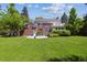 Large backyard with a well-maintained lawn, brick home, second-story porch, and mature trees at 2222 E 7Th Avenue Pkwy, Denver, CO 80206