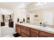 Bright bathroom featuring dual sinks, wood cabinets, and a large mirror at 8389 Owl Roost Ct, Parker, CO 80134
