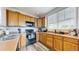 Modern kitchen with wood cabinets, black appliances, and a large window at 8865 Federal Blvd # 202, Westminster, CO 80260