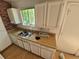 A dated kitchen with an undermount sink, and white cabinets with painted brick behind the sink at 3984 S Pitkin Way, Aurora, CO 80013