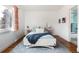 Bedroom with hardwood floors, a cozy bed, and bright natural light from a large window at 30 Eudora St, Denver, CO 80220