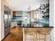 Bright kitchen boasts stainless appliances, blue backsplash, pendant lighting, and a breakfast bar with gold seating at 30 Eudora St, Denver, CO 80220