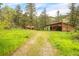A lush lot with trees and grass and a wooden cabin and outbuilding at 35106 Boulder Canyon Dr, Boulder, CO 80302