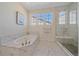 Spa-like bathroom featuring soaking tub with marble tile surround, glass shower, and neutral decor at 8016 Gore Creek Ln, Littleton, CO 80125