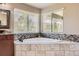 This main bathroom features a corner tub with tile surround and double windows at 6435 Spotted Fawn Run, Littleton, CO 80125