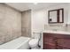 A bathroom features gray tile, a bathtub, toilet, vanity, and wood-look flooring at 2060 W Iliff Ave, Englewood, CO 80110