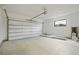 Spacious two car garage featuring a large door, concrete floor, small window and bright lighting at 1601 S Columbine St, Denver, CO 80210